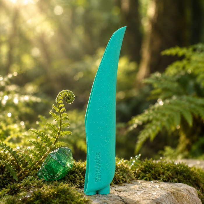 Bistoukette L'Essentielle coloris Verte pailletée sur une pierre moussue en sous-bois, près d'un cristal d'émeraude